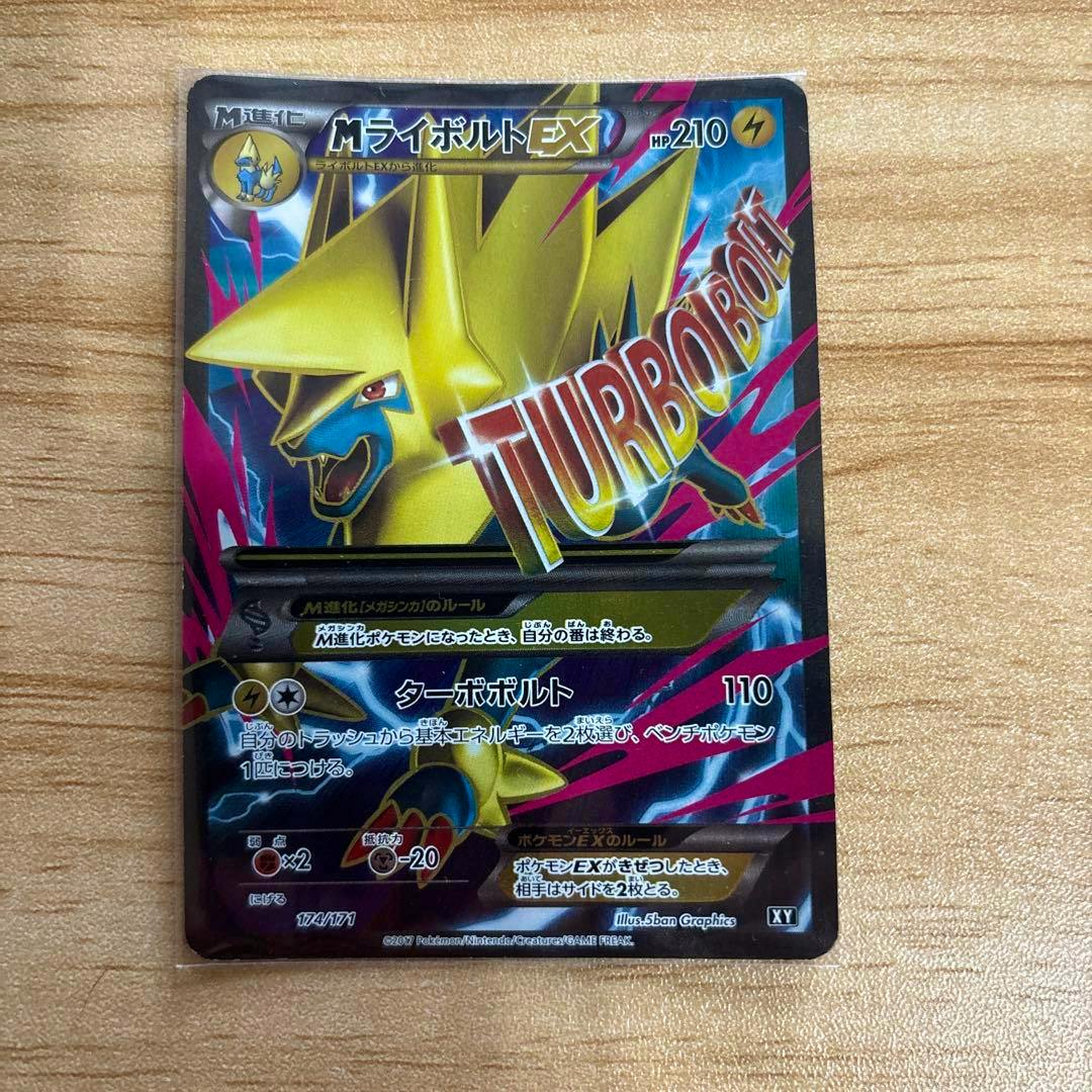 Photograph of the MライボルトEX THE BEST OF XY trading card front lying on a wooden surface, showing the full card artwork.