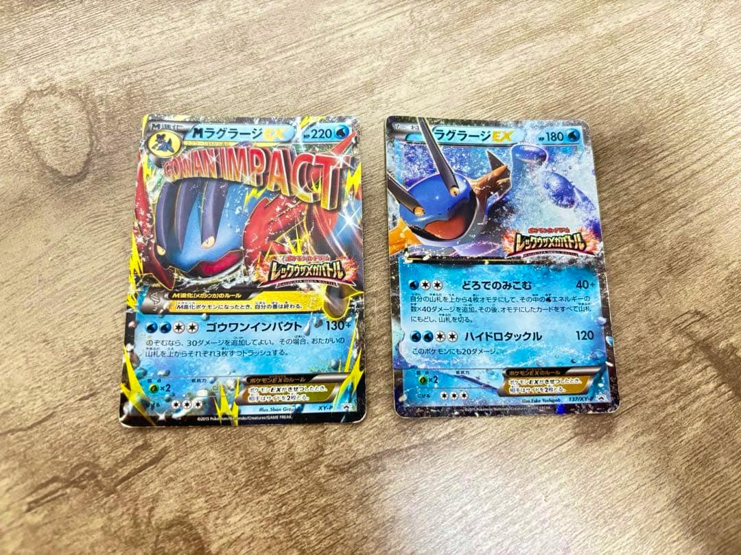 Two MラグラージEX trading cards (promo), placed side by side on a wooden surface showing Japanese text and artwork.