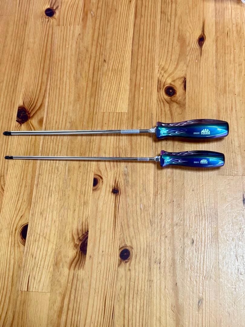 Two long Mac Tools screwdrivers with iridescent majora handles shown on a wooden surface.