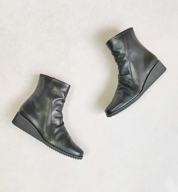 Two black synthetic leather ankle boots photographed on a light background.