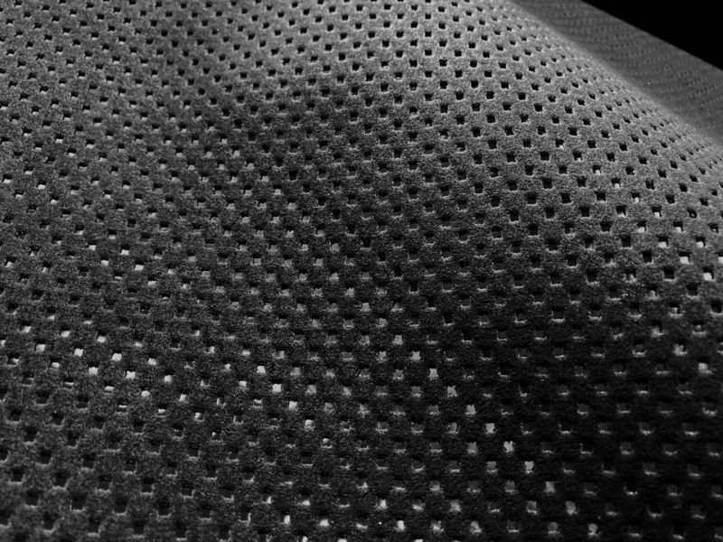 Close-up photo of black suede-like artificial leather fabric showing square perforations.