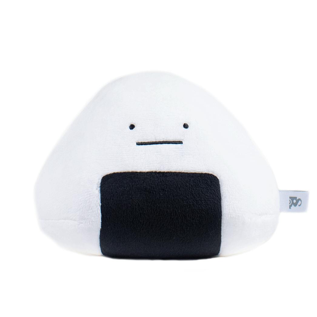Front view of a white onigiri-shaped plush toy with a simple embroidered face, a black nori patch on the front, and a small fabric tag on the side.