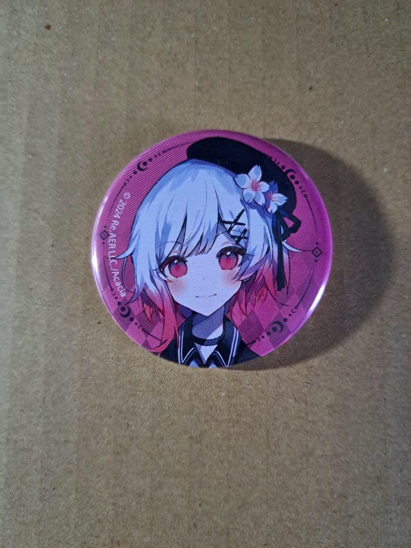 Front photo of a round pink glitter can badge depicting the character 桜庭エマ on a cardboard background.