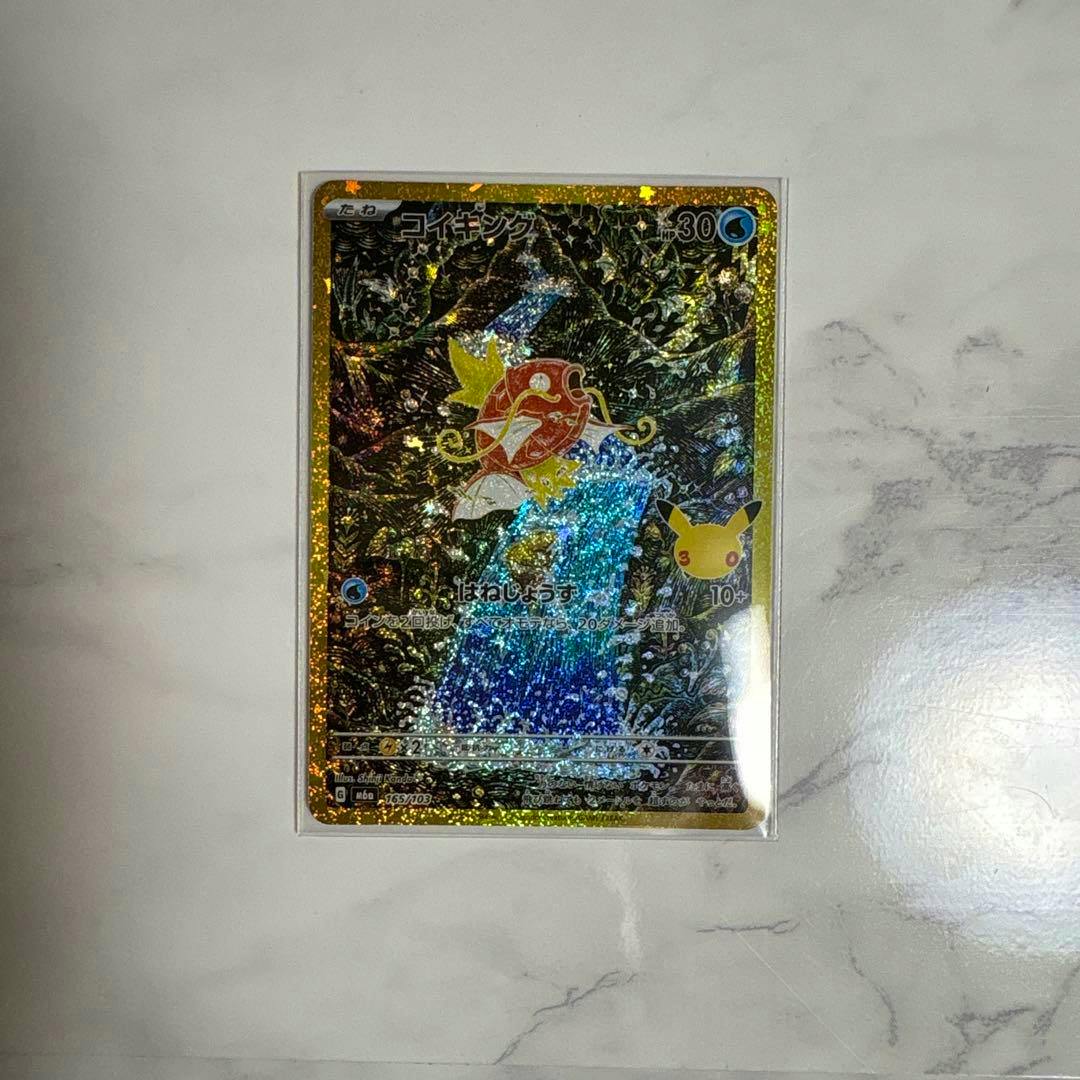 Holographic コイキング (Magikarp) Pokémon trading card front in a clear protective sleeve placed on a light marble surface.