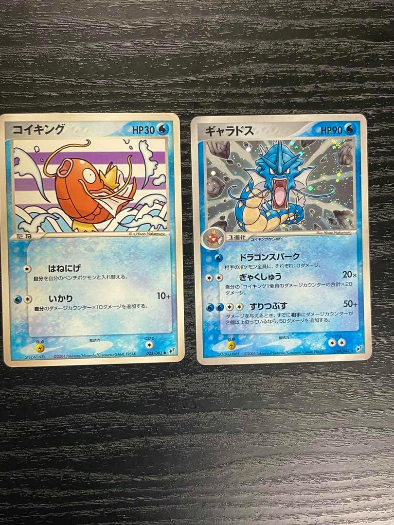 Two Japanese Pokémon trading cards, コイキング (Magikarp) and ギャラドス (Gyarados), shown side by side on a dark wood surface.