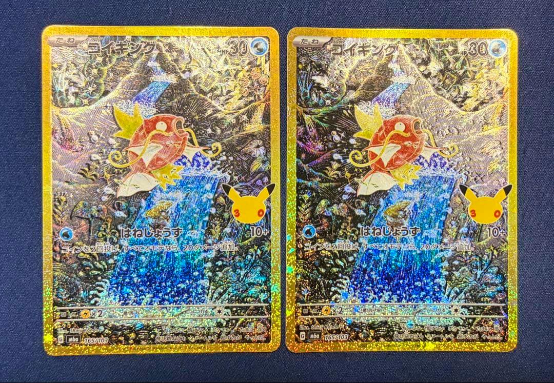 Two holographic Japanese コイキング (Magikarp) trading cards placed side-by-side on a dark surface.