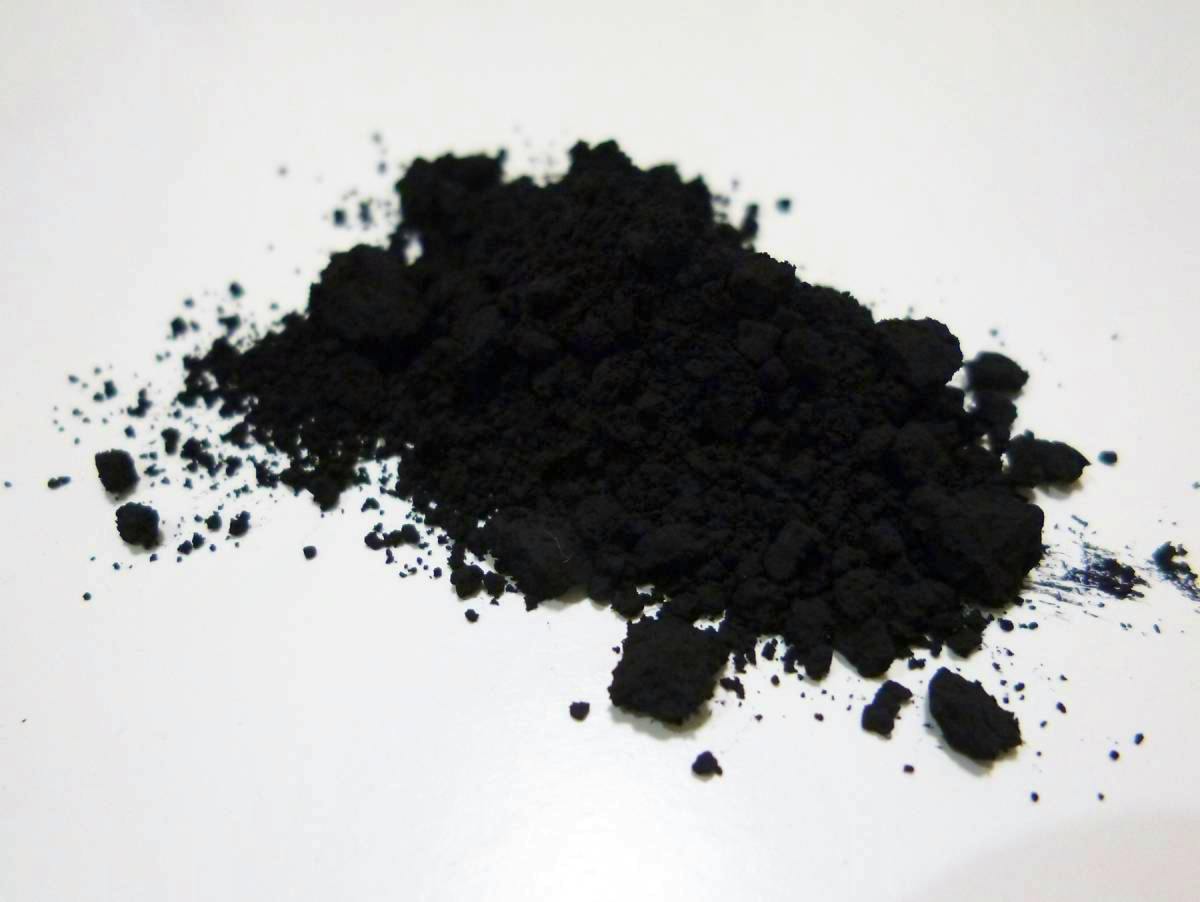 A small pile of black magnetite powder spread on a white surface.