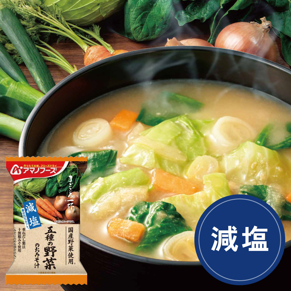 Steaming bowl of miso soup with vegetables and a single packaged serving of the powdered soup visible in the corner.