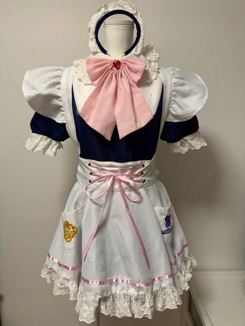 Front view of a navy and white maid dress with a white apron, pink bow, and headband displayed on a mannequin.