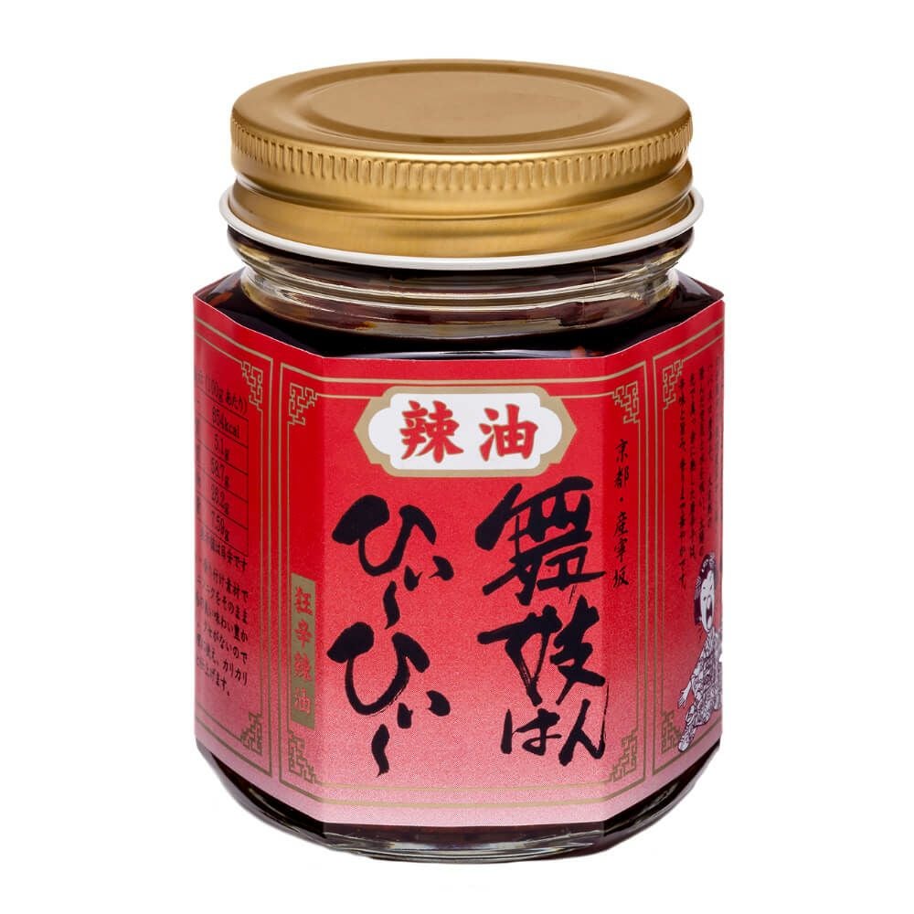Glass jar of chilli sauce with a red label and a gold screw lid displaying Japanese text.