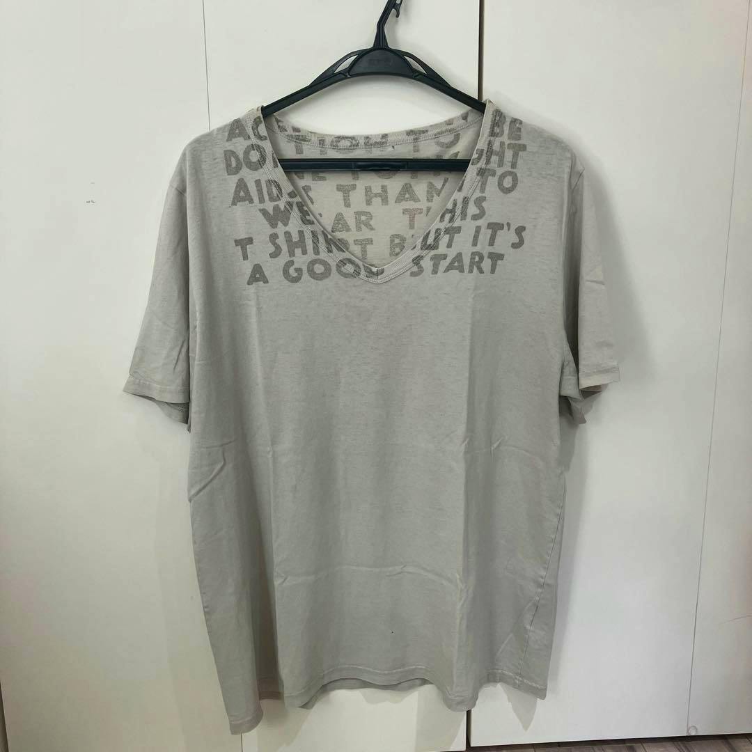Light gray cotton T-shirt with printed text and a V-neck hanging on a black hanger against a white background.