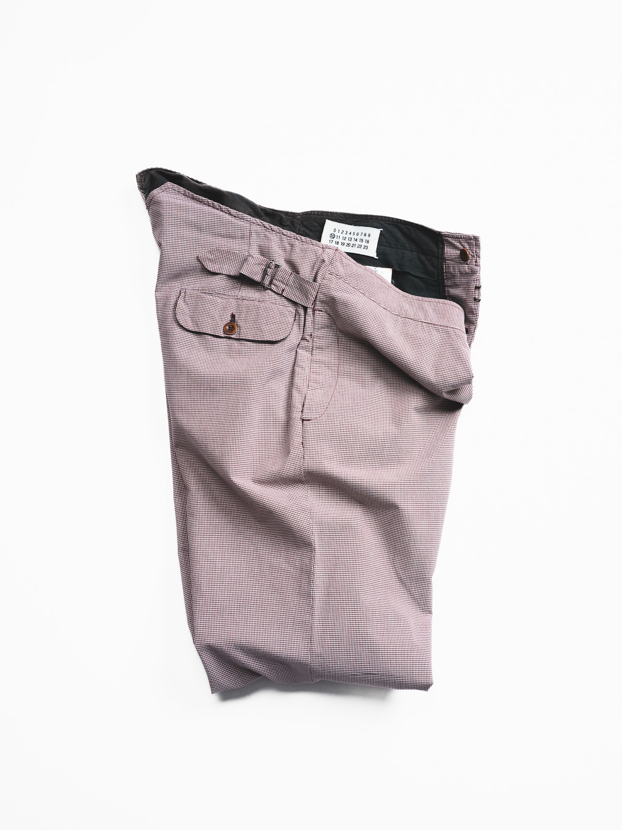 Folded checked-pattern men's trousers laid flat showing a back pocket, waistband label, and side adjuster.