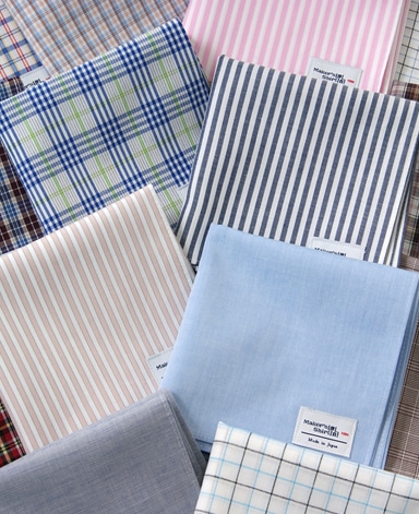 Folded cotton handkerchiefs in various striped and checked patterns arranged together.