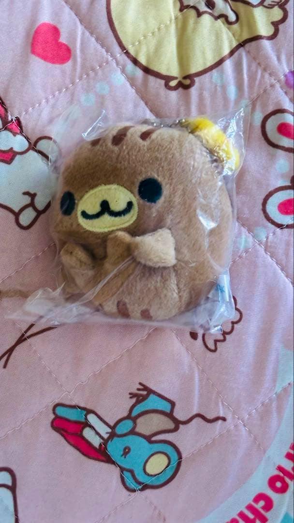 Sealed plush まめゴマ mirror (しまゴマ) keychain showing the character's front face on a pink patterned quilt background.