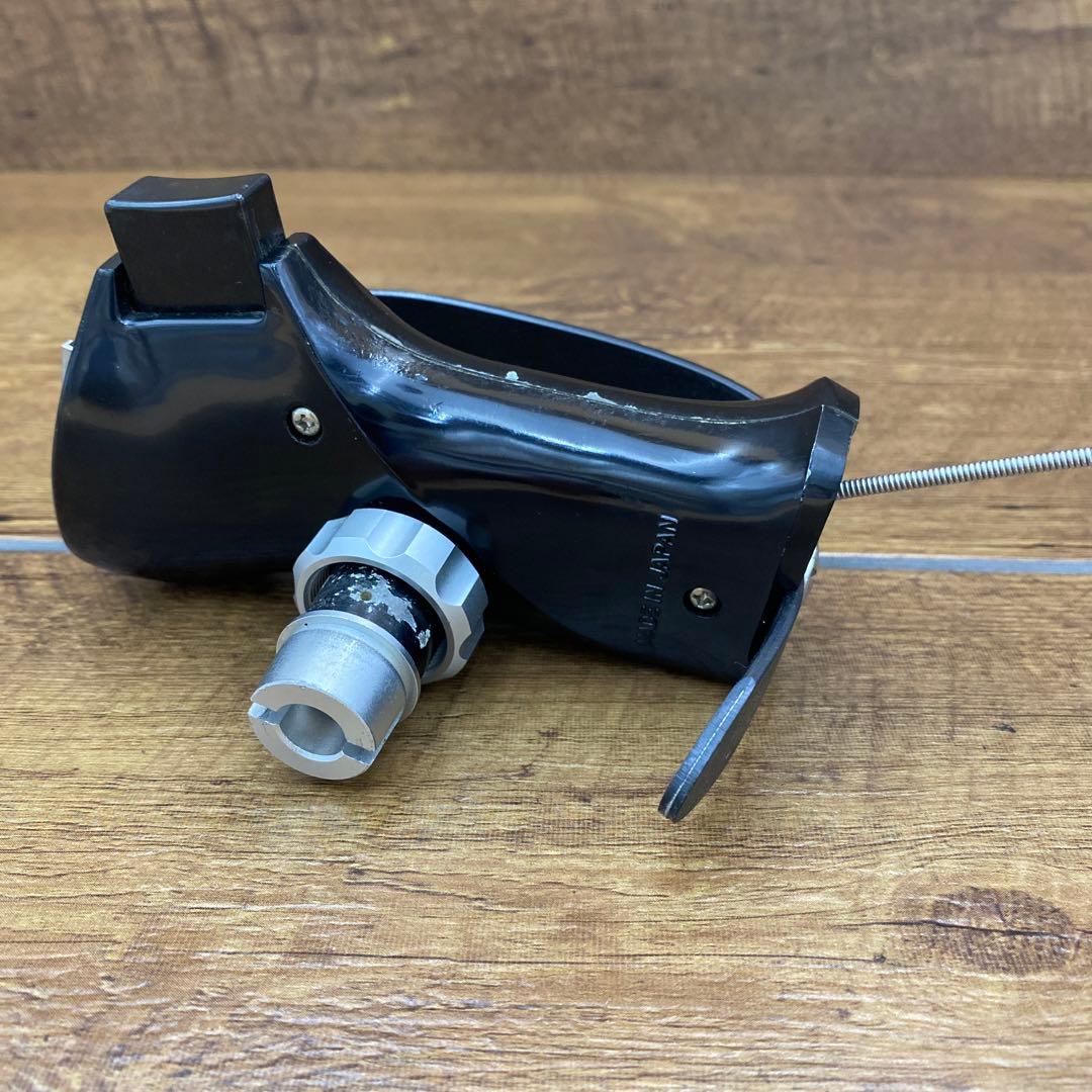 Black Mamiya camera hand grip L-63 with attached cable release shown on a wooden surface.