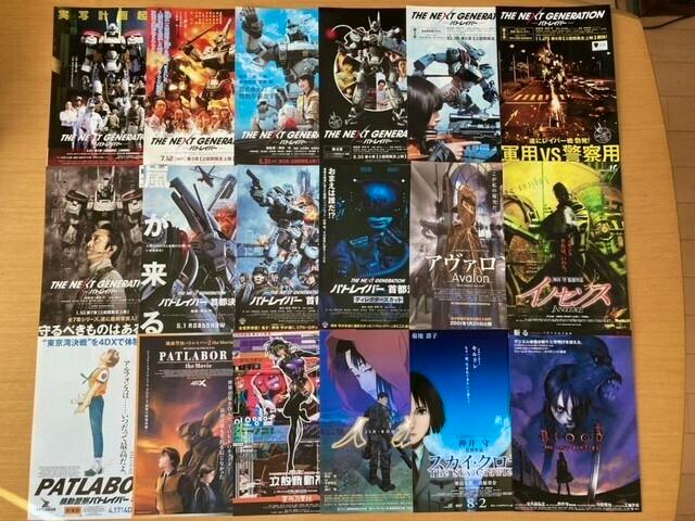 A grid of assorted flyers for Mamoru Oshii films laid out on a wooden surface.