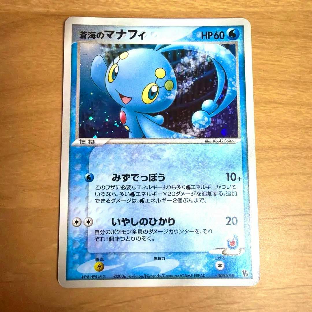 Photo of the trading card 蒼海のマナフィ 映画公開記念VSパック 005/019 showing the front of the card on a wooden surface.