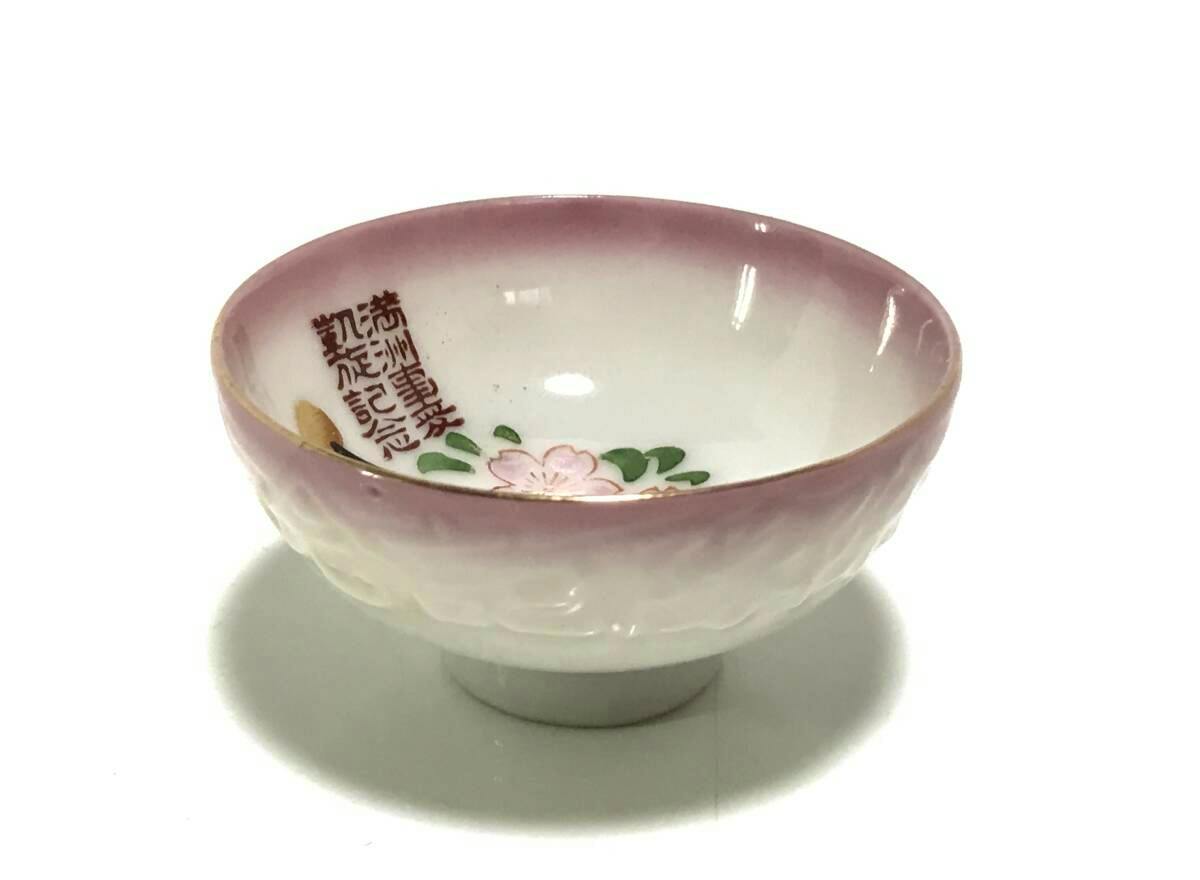 Ceramic plate with a pink rim, floral motif and Japanese inscriptions photographed on a white background.