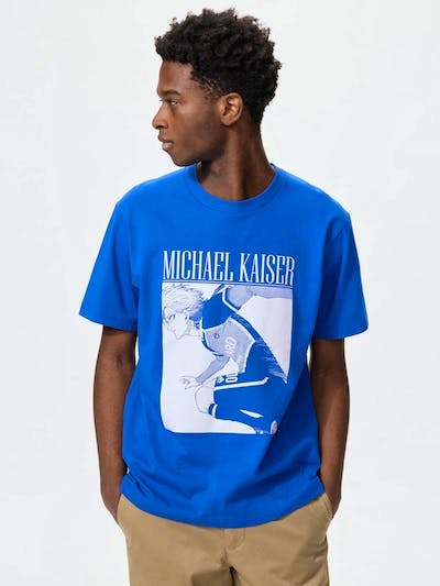 A blue cotton T-shirt with a white-and-blue manga-style graphic and 'MICHAEL KAISER' text worn by a male model.