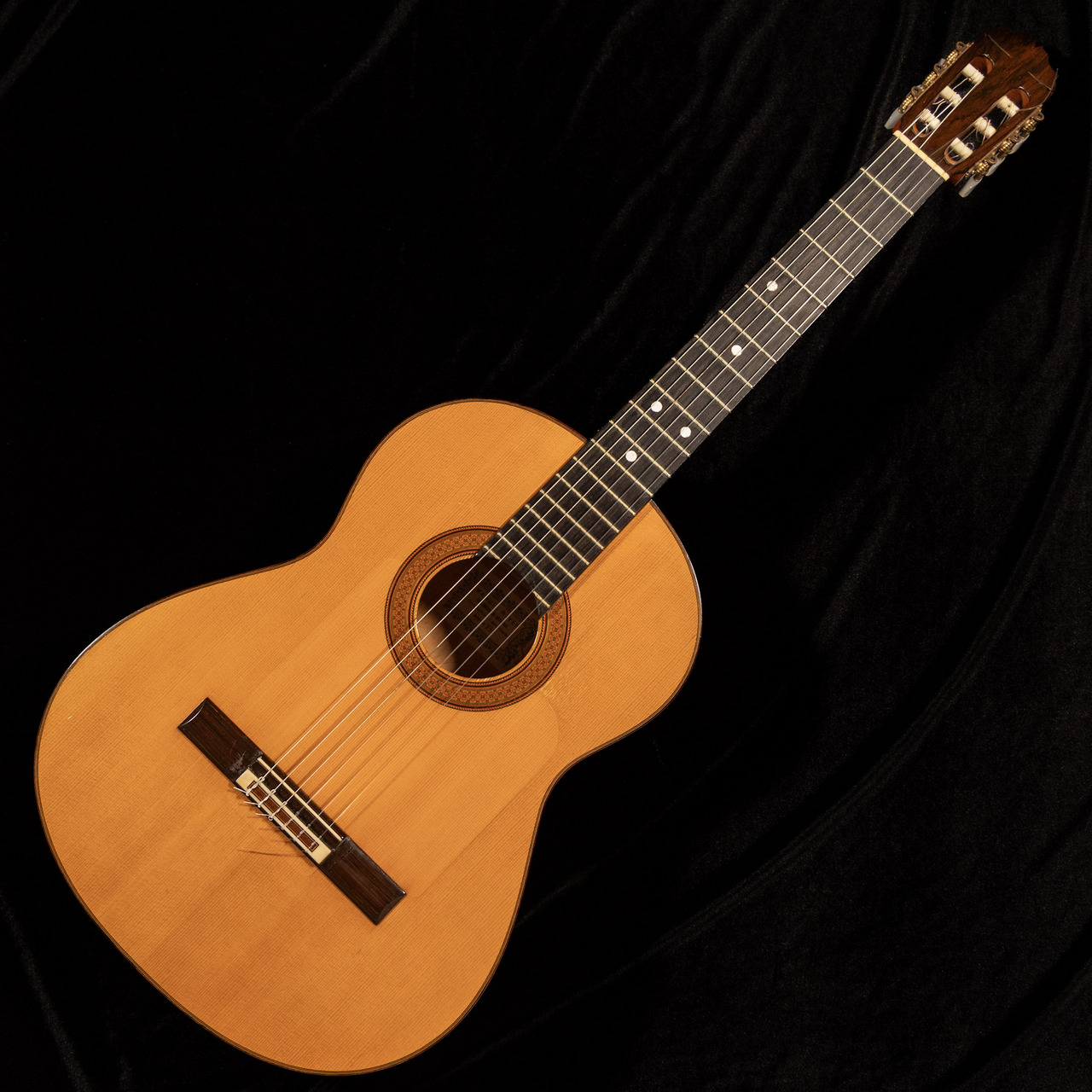 Front view photograph of the Manual Reyes flamenco acoustic guitar showing the full body, soundhole, fretboard, and headstock on a dark background.