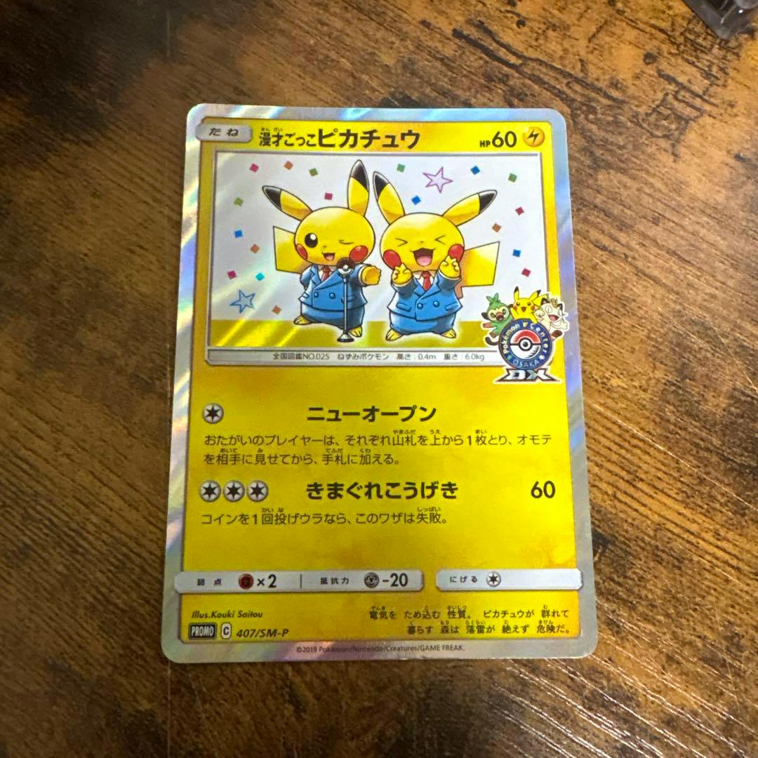 Front of a holographic Pokémon trading card showing two Pikachu wearing blue suits, photographed on a wooden surface.