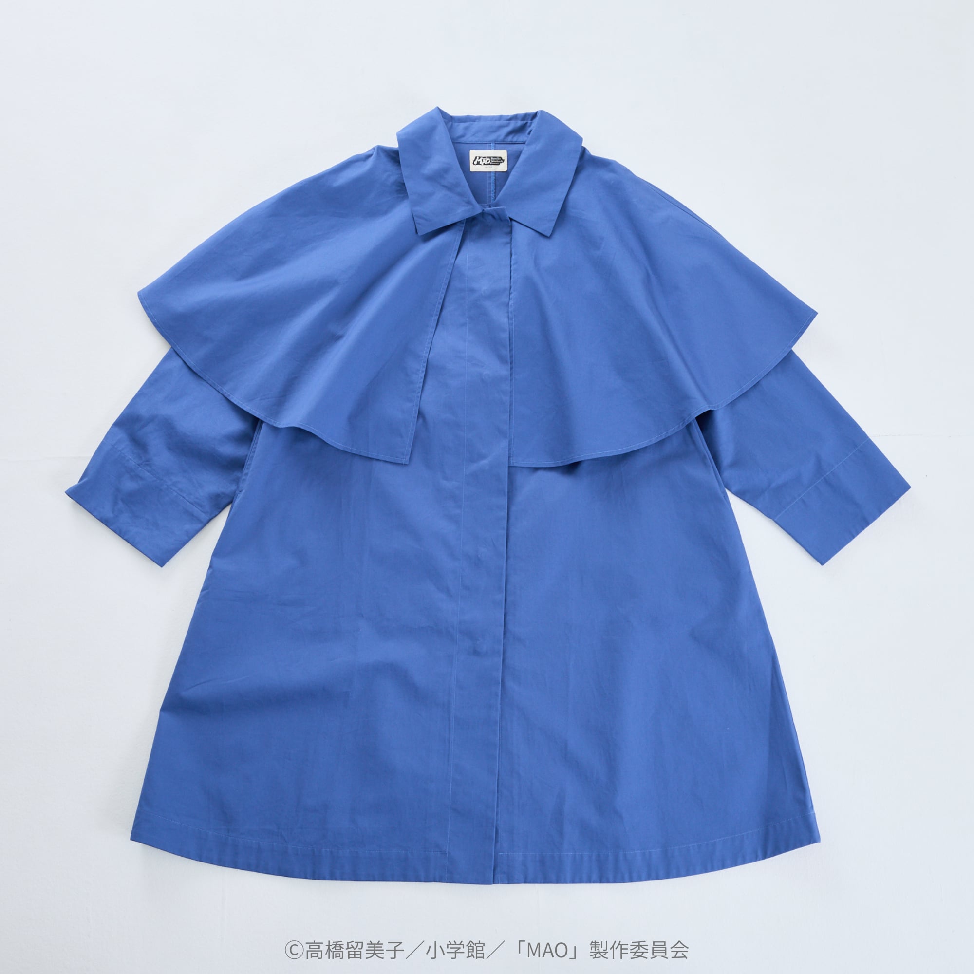 Front view flat-lay of the blue women's cotton coat with a short cape overlay and long sleeves.