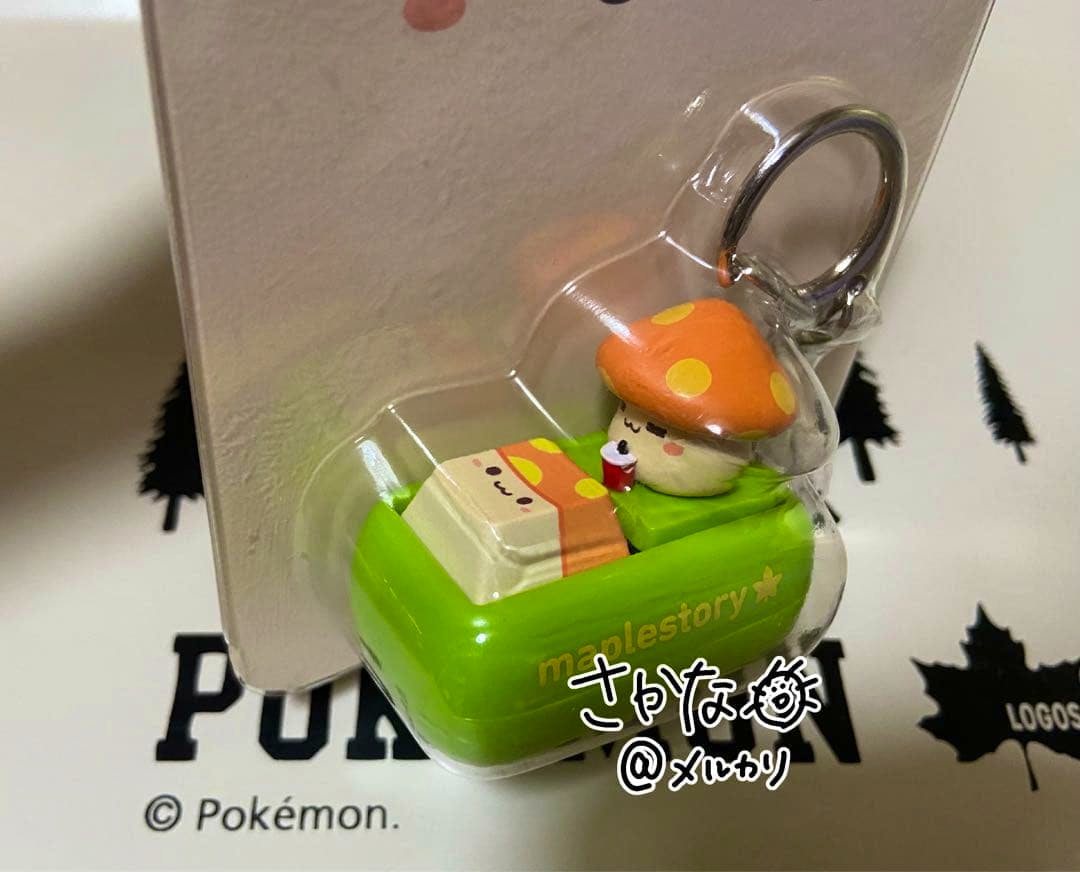 A MapleStory keycap keychain showing a mushroom character in a green plastic blister pack attached to a backing card.