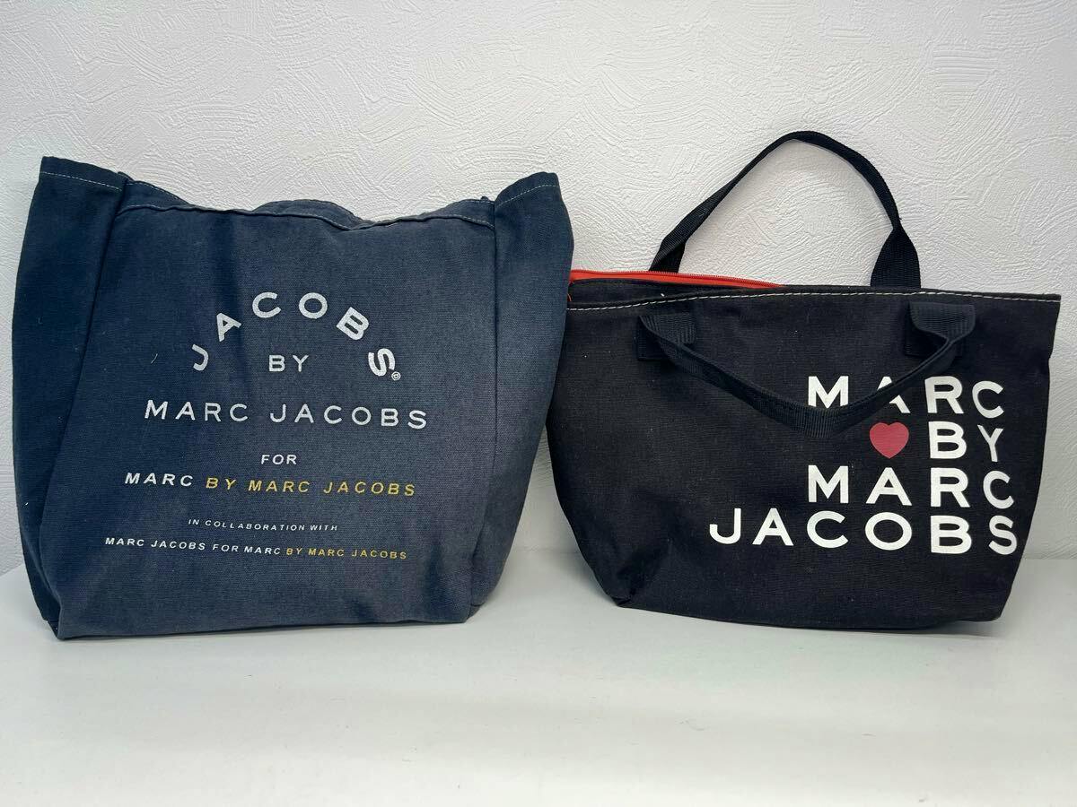 Two Marc by Marc Jacobs canvas tote bags shown side by side on a white surface.
