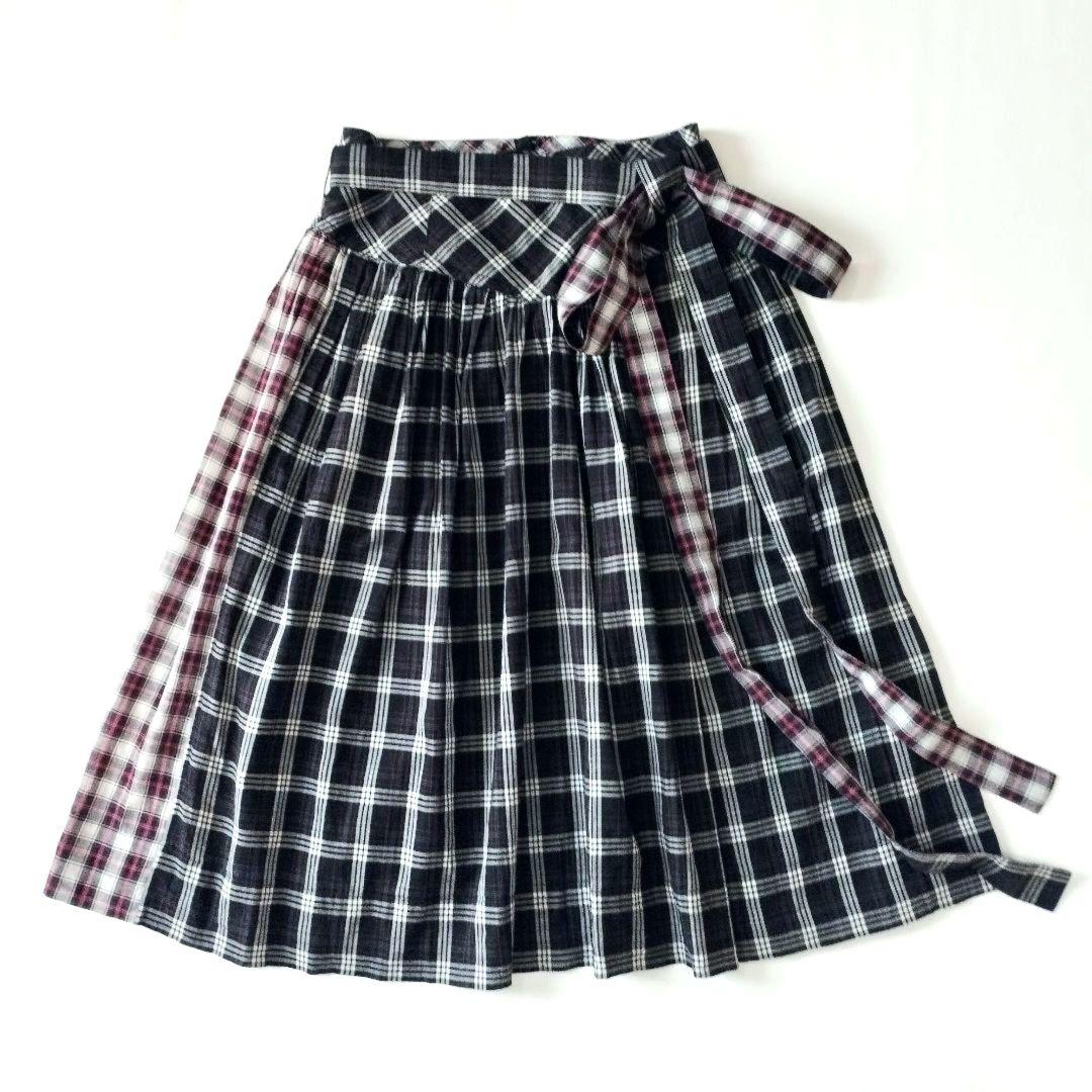 Black-and-white checked cotton women's skirt with pleats and a side tie, laid flat on a white background.