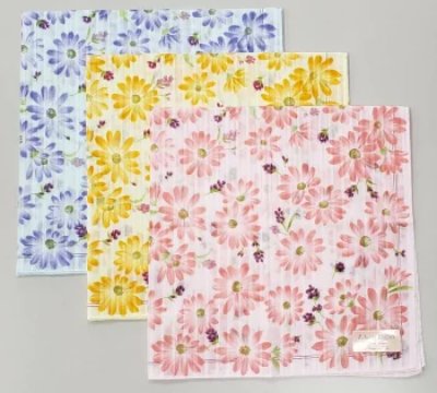 Three cotton handkerchiefs with daisy (margaret) floral prints in pink, yellow, and blue arranged flat.