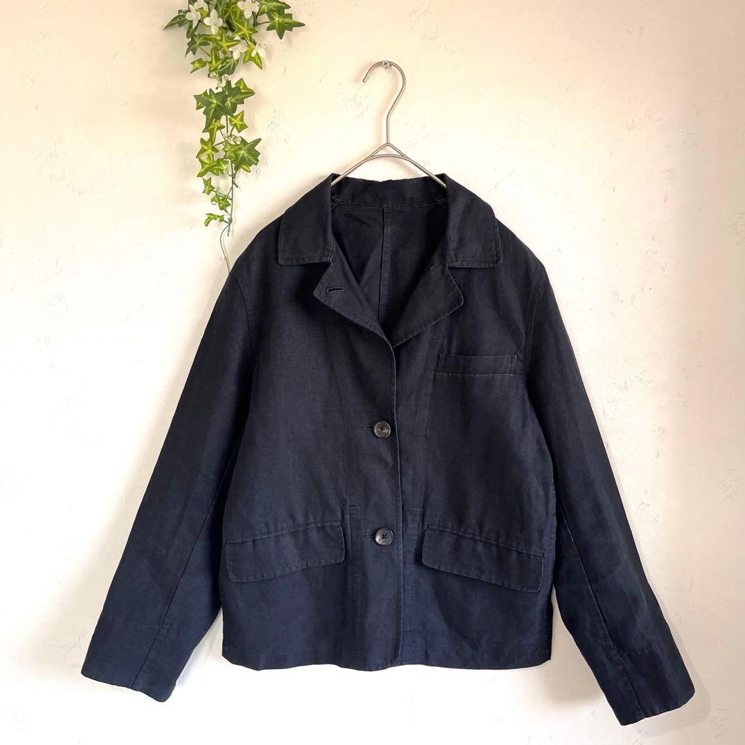 MARGARET HOWELL men's linen tailored jacket hanging on a hanger against a light-colored wall.
