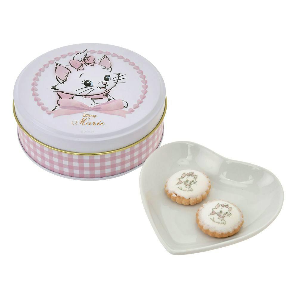 A round decorative tin featuring Marie the cat next to a heart-shaped dish holding two biscuits printed with Marie.