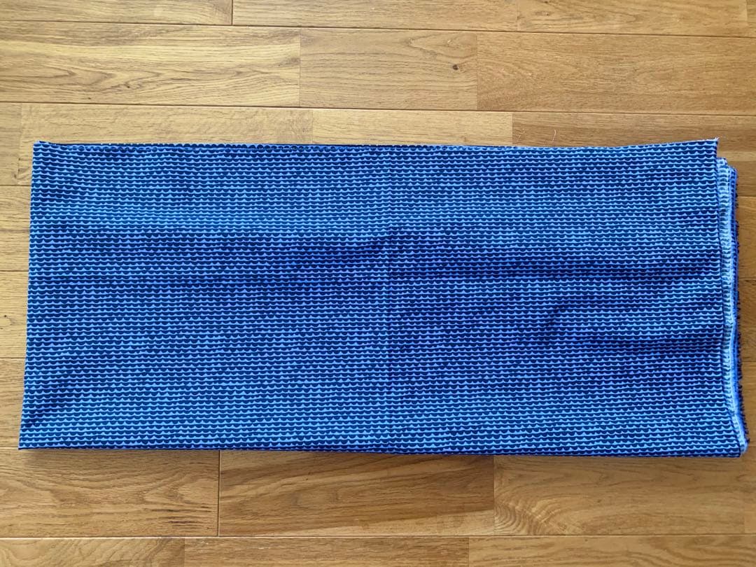 Folded blue Marimekko Papayo patterned cotton fabric laid on a wooden floor.