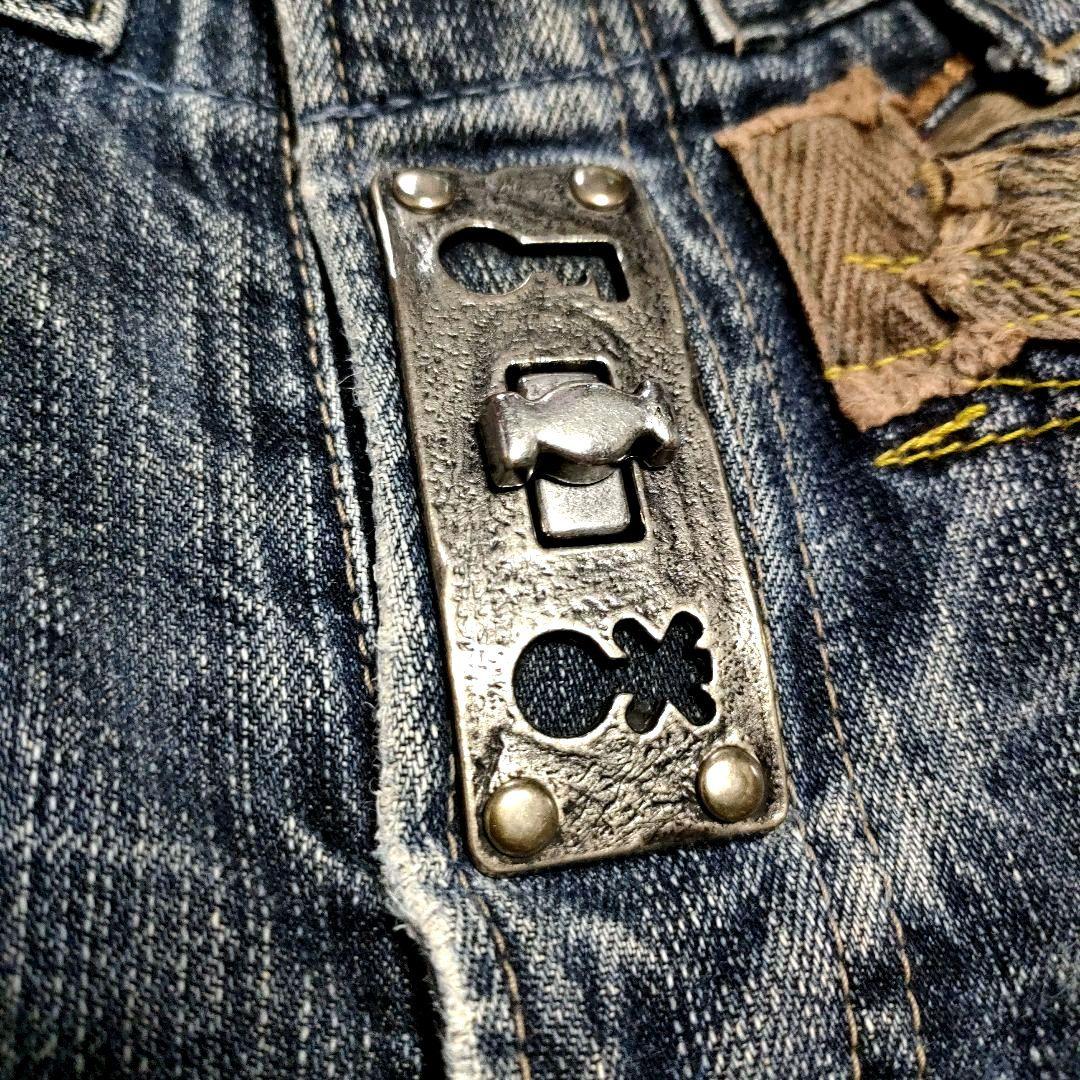 Close-up of a metal turnlock attached to blue denim of the men's pants.