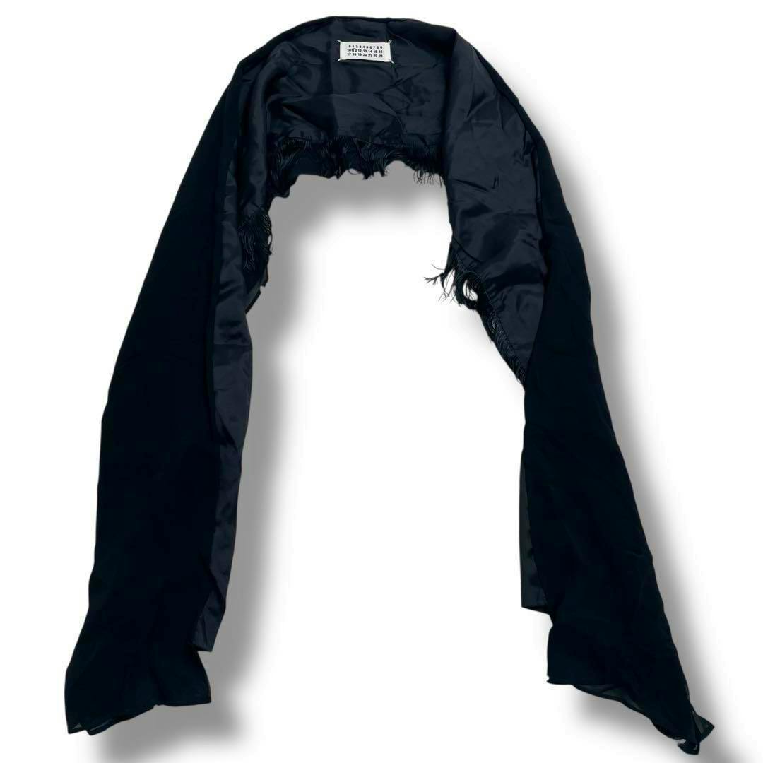 Black wool scarf (Martin Margiela) laid on a white background showing the interior label and frayed edges.