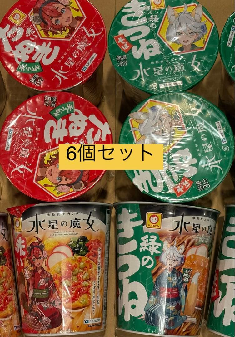 Photo of six Maruchan instant noodle cups from the Suisei no Majo collaboration (red and green varieties) arranged in a box with a yellow “6個セット” label.
