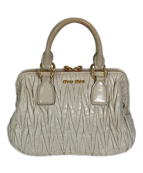 Cream matelassé cow leather handbag with two top handles and gold-tone hardware shown from the front.