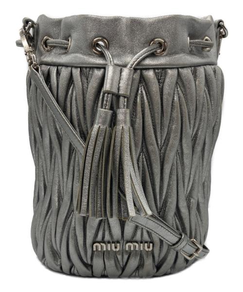 Front view of a matelassé cow leather shoulder bucket bag with drawstring tassels and a shoulder strap.