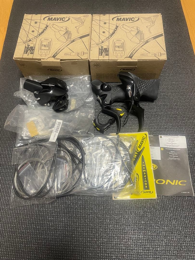 Pair of MAVIC mechatronic brake/shifter levers with cables, manuals, and two MAVIC boxes arranged on a mat.
