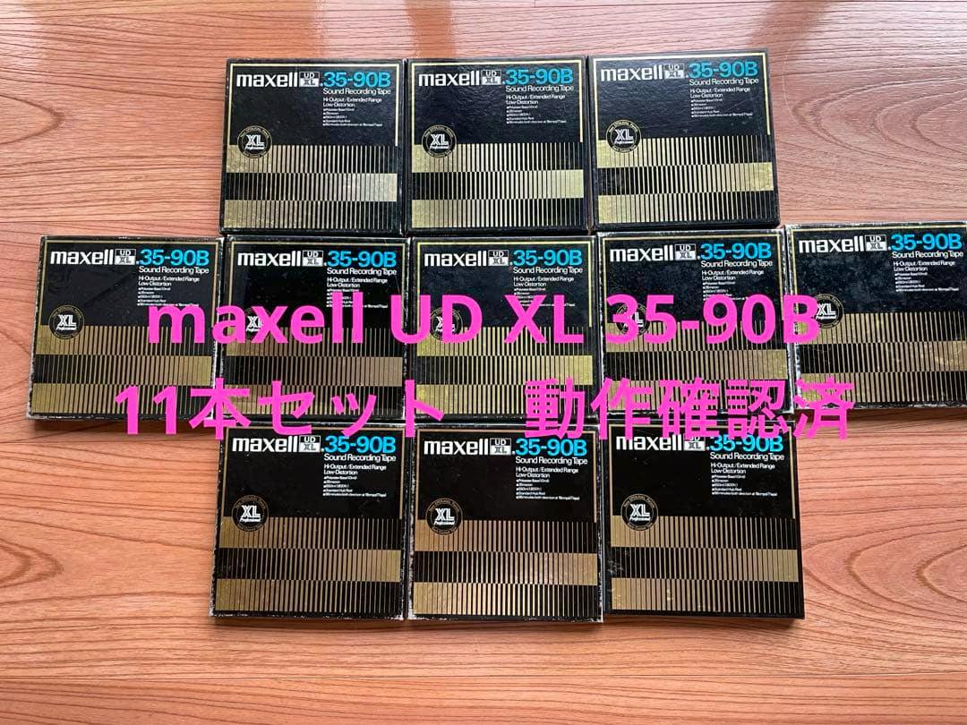 Photo of eleven Maxell UD XL 35-90B cassette tape boxes arranged on a wooden surface with pink overlaid text.