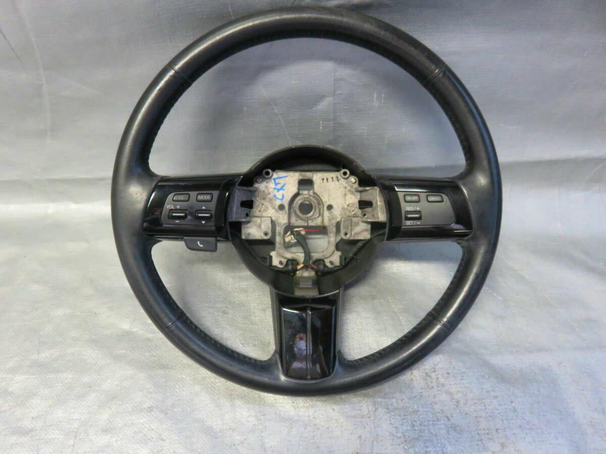 Front view of a used Mazda CX-7 ER3P steering wheel without airbag, showing control buttons and exposed center hub.