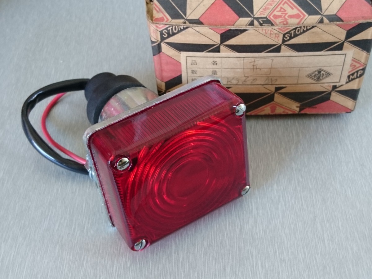 Square red tail lamp for a Mazda K360 displayed with wiring and its original box on a gray surface.