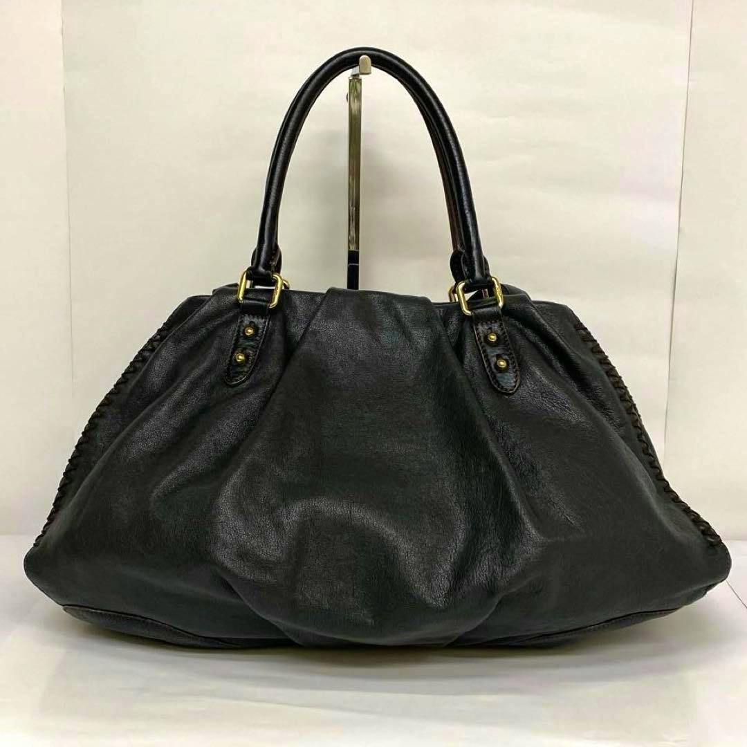 Black cow leather MCM 2-way handbag with dual top handles and shoulder strap on a white backdrop.