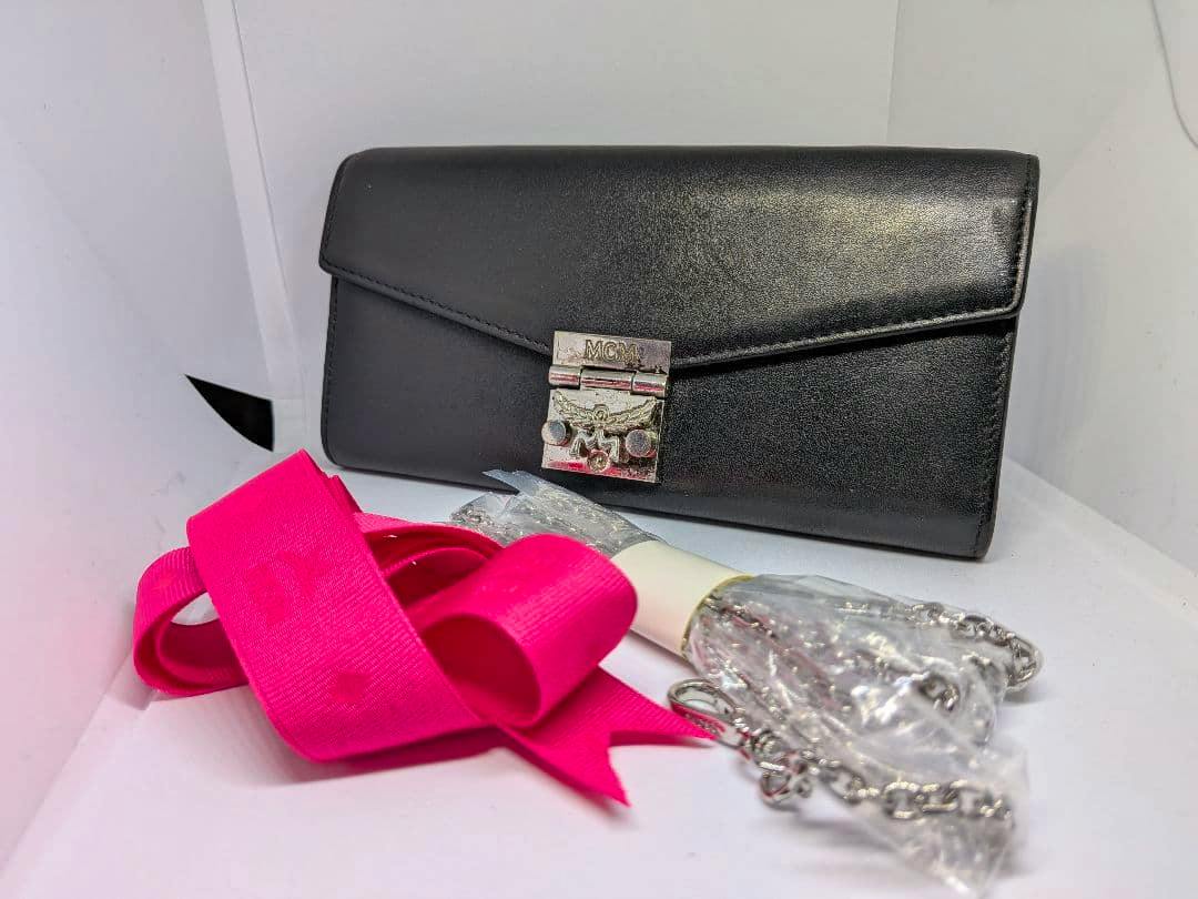 Black MCM leather long wallet shown with a pink strap ribbon and a wrapped silver chain strap.
