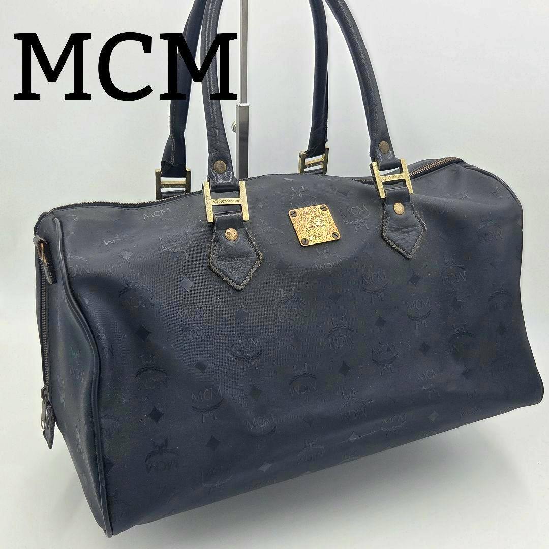 Black MCM monogram (Visetos) mini boston travel bag shown from the front with top handles and gold-tone hardware.