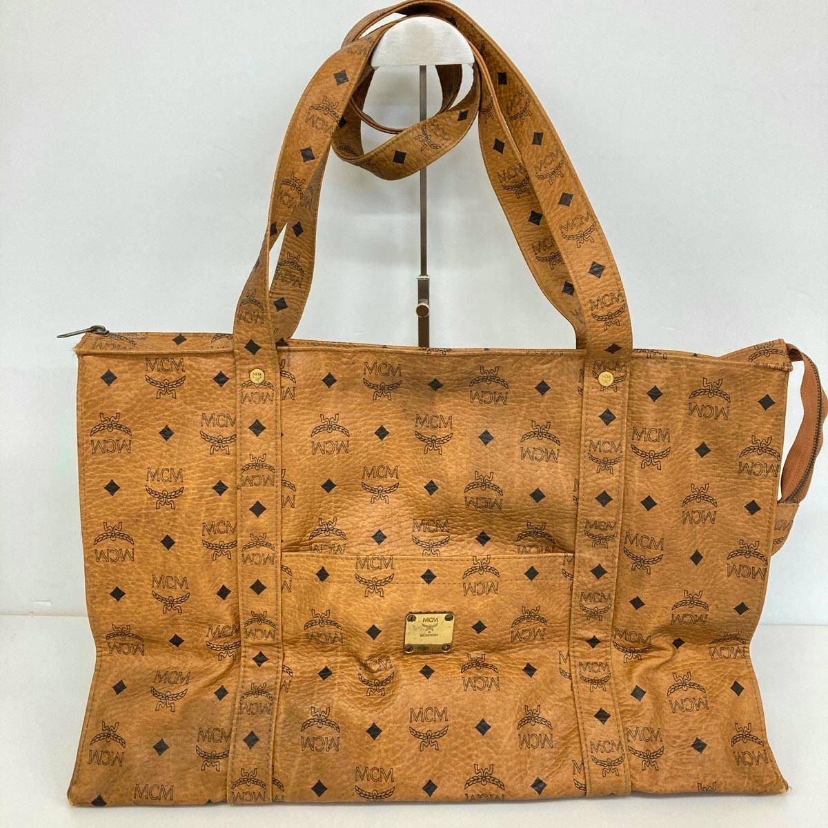 Front view of a brown MCM Visetos-patterned tote/shoulder bag showing straps and a gold logo plate.