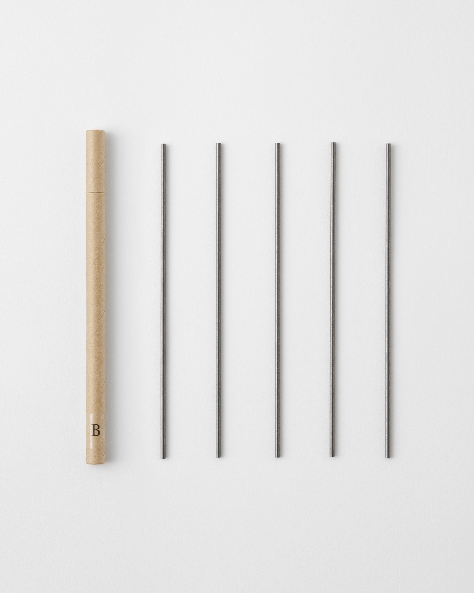 A cardboard tube and five pencil refills arranged on a white background.