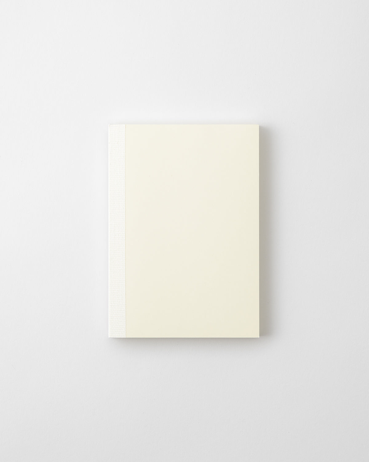 Top-down photo of an MD Notebook (A6) with an off-white cover and a white spine on a light background.