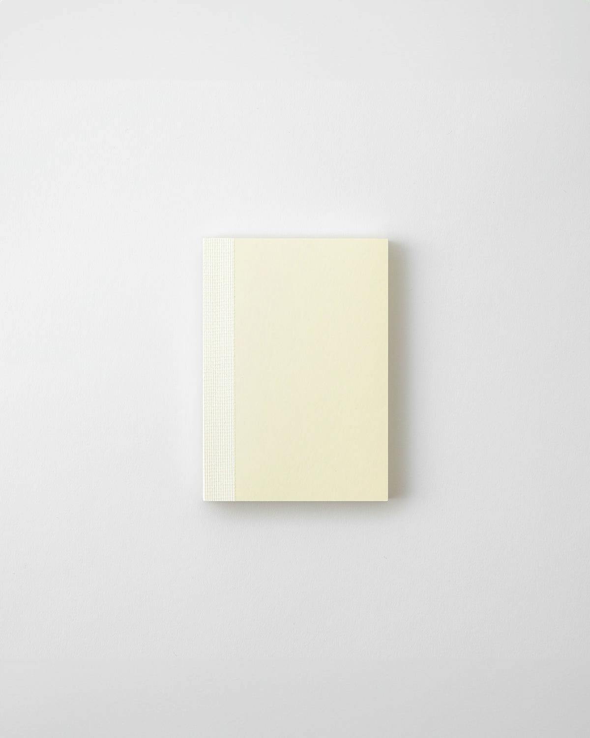 A closed MD Notebook (A7) with a cream cover and a textured spine placed on a white background.
