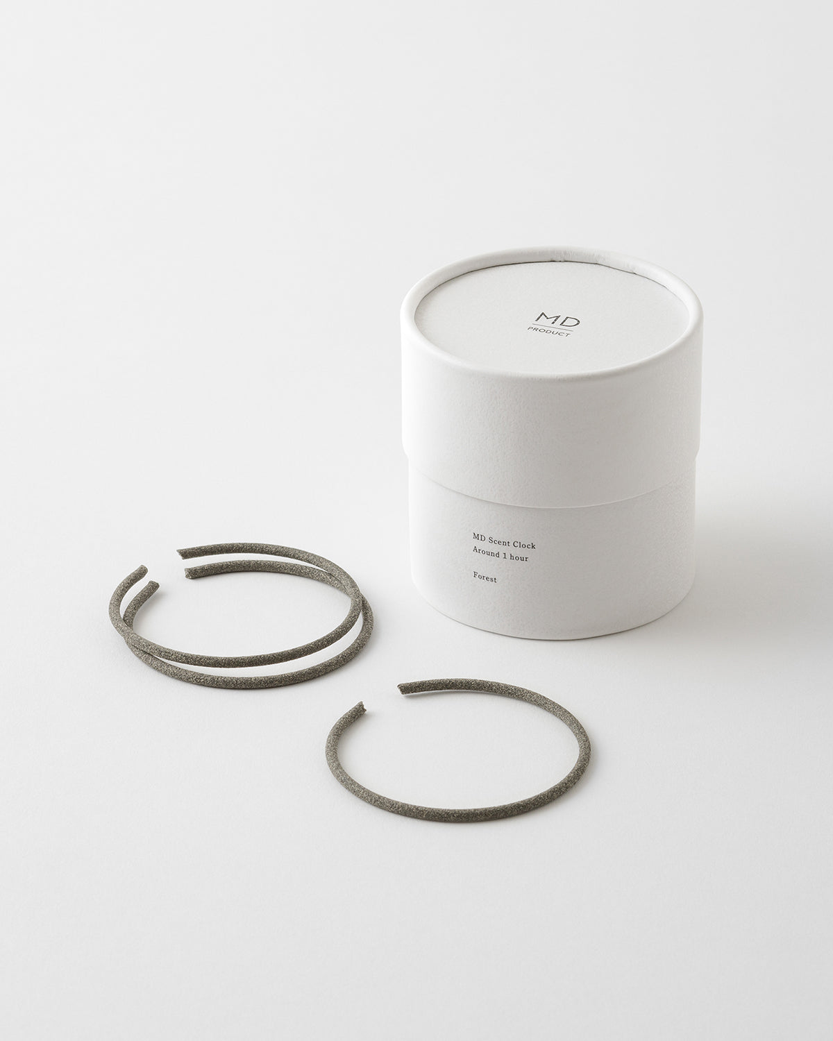 MD Scent Clock white cylindrical box shown with three grey ring-shaped incense coils.